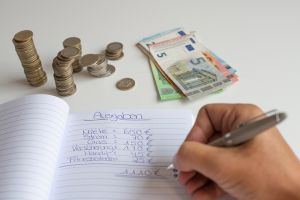 © Sarah - stock.adobe.com Person schreibt in Haushaltsbuch